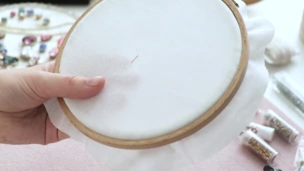 Woman begins to embroider flowers on canvas using hoops. Girl embroidery on fabric, using a hoop, a needle and thread. Flower pattern on textiles. Home needlework. Homemade crafts, handmade art - Footage, Video