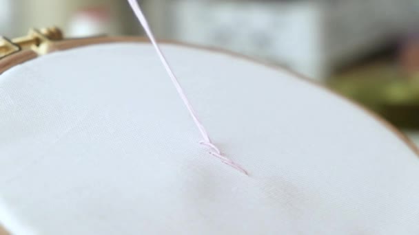 Крупным планом женской руки мастер вышивает узоры на ткани с цветными нитями. Дизайнер делает украшения ручной работы - Кадры, видео