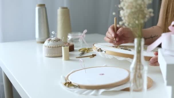 Young girl sits on workspace in light workshop and embroiders with beads. designer makes handmade jewelry. Hobby concept. Self-employed freelancer makes creativity - Footage, Video