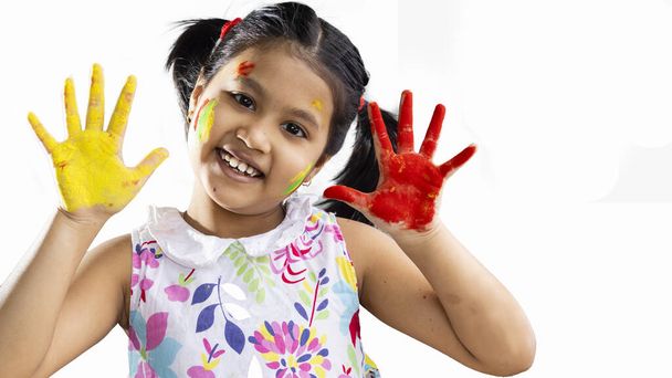 Une fille indienne mignonne enfant montrant des paumes colorées pendant holi sur fond blanc - Photo, image