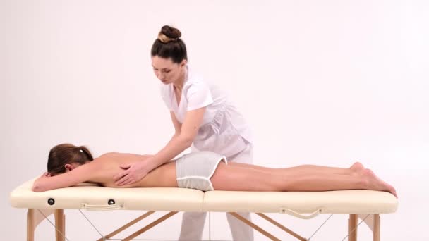 Jonge vrouw met massage in spa salon. Close-up van de vrouw ontspannen tijdens rugmassage liggend op massagetafel in slow motion. - Video