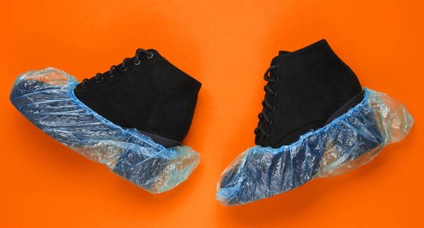 Black suede boots with shoe covers on orange background. Over view - Photo, Image