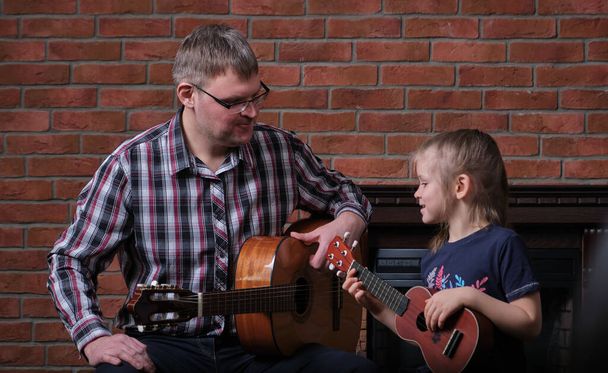 La bambina e suo padre suonano la chitarra. Imparare a suonare la chitarra. Educazione musicale e lezioni extra-curriculari. - Foto, immagini