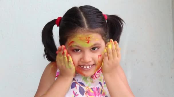 Roztomilé indické dívka dítě hrát s barvami během holi na bílém pozadí - Záběry, video