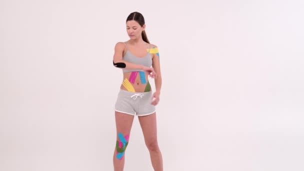 肘に示す若いフィット女性は弾性運動テープを適用しました。光を背景にした運動療法 - 映像、動画