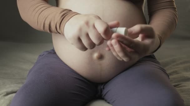 Mujer embarazada lubrica gran vientre embarazada con crema para estrías - Imágenes, Vídeo