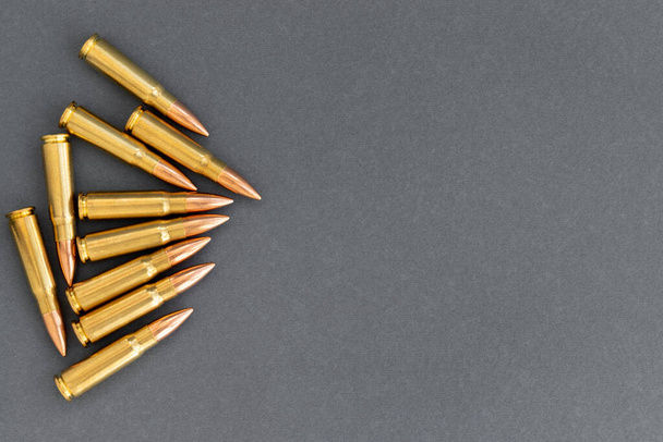 Grupo de balas sobre fundo de papel cinzento. Cartuchos calibre 7.62 para espingarda de assalto Kalashnikov, banner modelo com espaço de cópia - Foto, Imagem