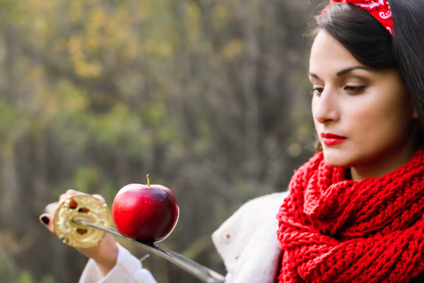 Egy alma a kard szélén egy fiatal nő kezében. Japán kard. - Fotó, kép