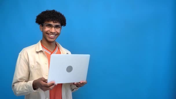 щасливий афроамериканський чоловік тримає ноутбук ізольований на синьому
 - Кадри, відео