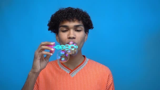 šťastný africký Američan foukání mýdlo bubliny izolované na modré - Záběry, video