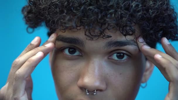 bijgesneden weergave van doorboorde Afrikaanse Amerikaanse man styling wenkbrauwen geïsoleerd op blauw - Video