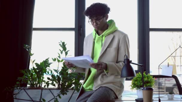стильний афроамериканський ілюстратор дивиться на ескізи в офісі
 - Кадри, відео