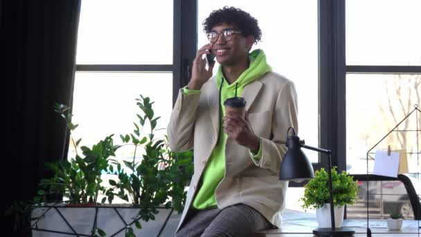 šťastný africký americký podnikatel mluví na smartphone v úřadu - Záběry, video