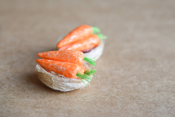 Figuras pequeñas hechas a mano de zanahoria y champiñones en nidos sobre fondo natural neutro con espacio de copia vacío - Foto, imagen