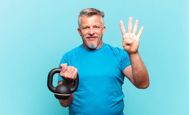 senior athlete man smiling and looking friendly, showing number four or fourth with hand forward, counting down - Foto, Imagen