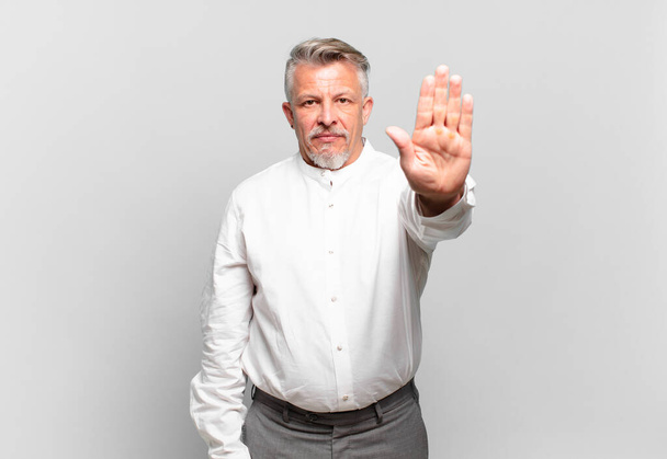 senior businessman looking serious, stern, displeased and angry showing open palm making stop gesture - 写真・画像