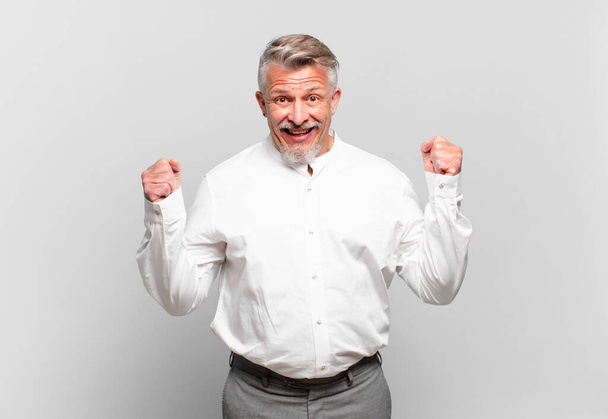 senior businessman feeling shocked, excited and happy, laughing and celebrating success, saying wow! - Fotoğraf, Görsel