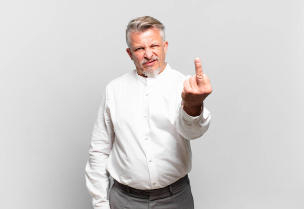 senior businessman feeling angry, annoyed, rebellious and aggressive, flipping the middle finger, fighting back - Foto, Bild