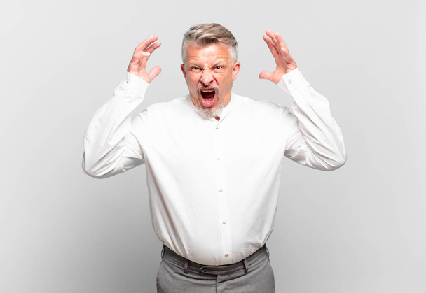 senior businessman screaming with hands up in the air, feeling furious, frustrated, stressed and upset - Foto, imagen