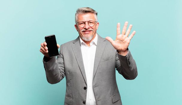 senior businessman smiling and looking friendly, showing number five or fifth with hand forward, counting down - Photo, image