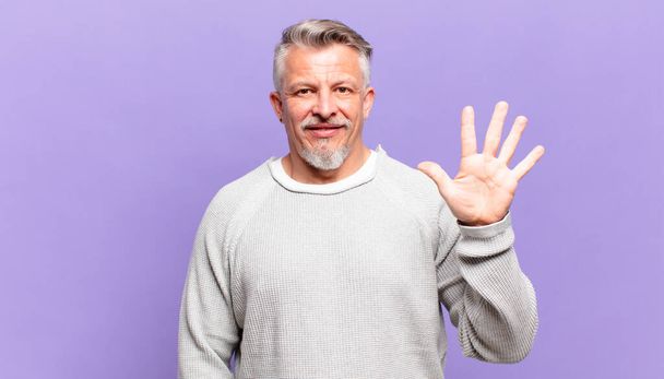 old senior man smiling and looking friendly, showing number five or fifth with hand forward, counting down - Фото, изображение