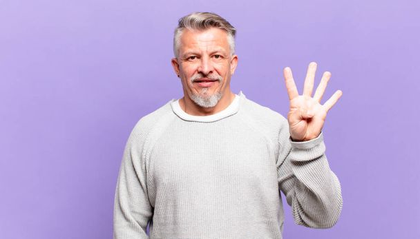 old senior man smiling and looking friendly, showing number four or fourth with hand forward, counting down - Фото, изображение