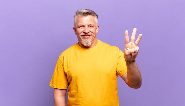 idős férfi mosolyog és barátságos, mutatja a harmadik vagy harmadik kéz előre, visszaszámlálás - Fotó, kép