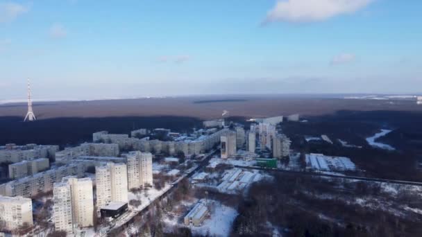 Vista aérea de izquierda a derecha Kharkiv centro de la ciudad y Pavlove Pole, distritos de Sokolniki. Edificios de varios pisos cerca del bosque con antena de torre de telecomunicaciones con cielo brillante escénico en invierno - Metraje, vídeo