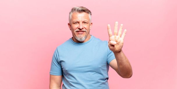 old senior man smiling and looking friendly, showing number four or fourth with hand forward, counting down - Фото, изображение