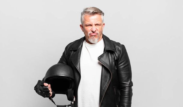 senior motorbike rider feeling sad, upset or angry and looking to the side with a negative attitude, frowning in disagreement - Фото, зображення