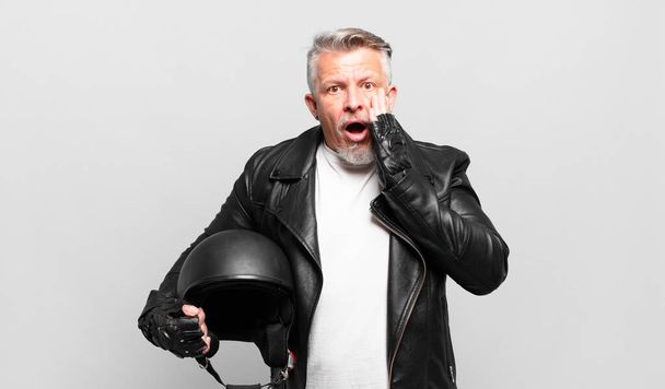 senior motorbike rider feeling shocked and scared, looking terrified with open mouth and hands on cheeks - Foto, imagen