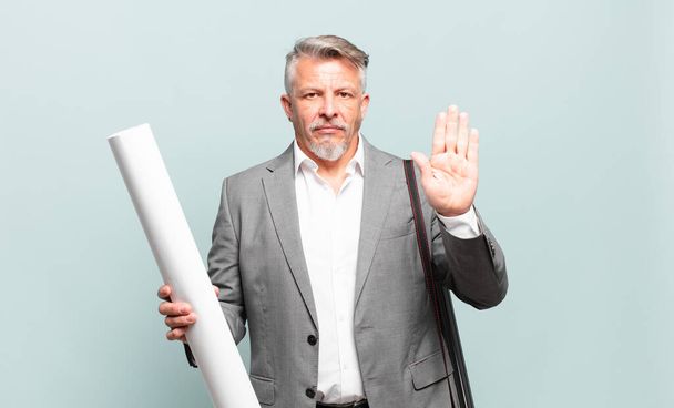 senior architect looking serious, stern, displeased and angry showing open palm making stop gesture - 写真・画像
