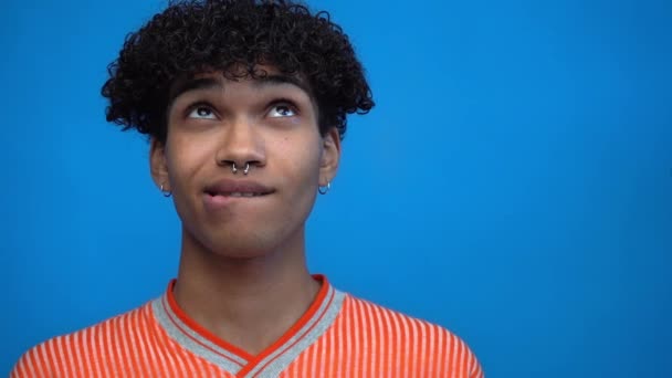 slow-motion de songeur afro-américain mordant lèvres isolées sur bleu - Séquence, vidéo