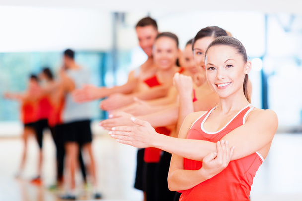 Group of smiling people stretching in the gym - Фото, изображение