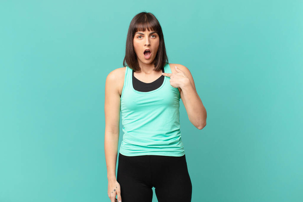 athlete woman looking shocked and surprised with mouth wide open, pointing to self - Фото, изображение