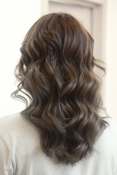 brun clair cheveux longs bouclés lâches photo de gros plan dans le salon de coiffure vue arrière - Photo, image