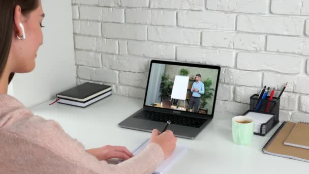 Mujer estudio en casa en línea videollamada portátil, escribe en cuaderno escuchar profesor - Imágenes, Vídeo