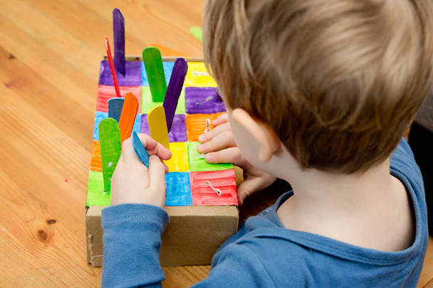 Montessori végrehajtása. A színek alapján válogatok. Otthoni barkácsolás kartondobozból és jégkrém pálcikából. Könnyű 5 perces kézműves. Korai óvodai eduáció kisgyermekek számára. - Fotó, kép