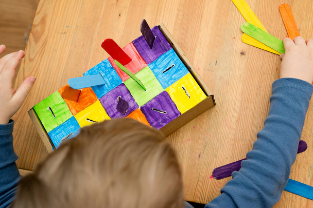 Montessori végrehajtása. A színek alapján válogatok. Otthoni barkácsolás kartondobozból és jégkrém pálcikából. Könnyű 5 perces kézműves. Korai óvodai eduáció kisgyermekek számára. - Fotó, kép