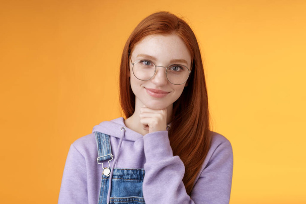 Sebevědomý šťastný uvolněný evropský ryšavý zručný mladá žena podnikatelka brýle vytvořit startup usmívat potěšený vzhled potěšený výsledek dotek bradu přemýšlivý inteligentní, oranžové pozadí - Fotografie, Obrázek