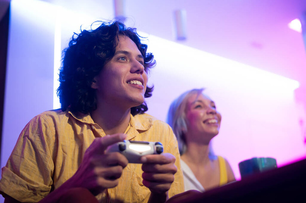 Πορτρέτο του συναισθηματικού νεαρό ζευγάρι παίζει βιντεοπαιχνίδι στο σπίτι. - Φωτογραφία, εικόνα