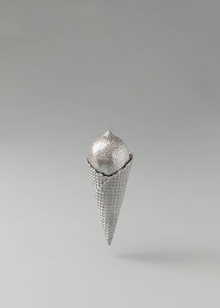 Silver ice cream cone with lemon against gray background. Minimal food concept. Copy space. - Photo, Image