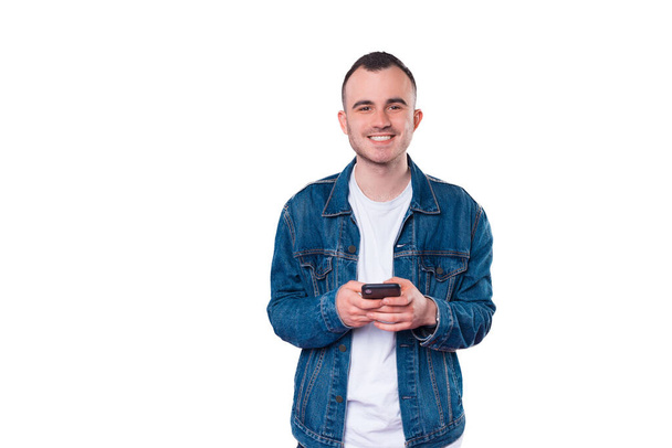Foto de un joven guapo sonriendo y usando un teléfono inteligente. - Foto, imagen