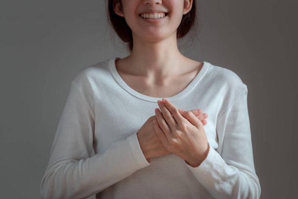Mujer asiática pone su mano en el pecho para apoyar la causa del cáncer de mama. Concepto de concienciación sobre salud, medicina y cáncer de mama. - Foto, Imagen