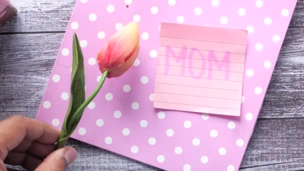 Muttertagsgeschenk und Blume von oben auf dem Tisch. - Filmmaterial, Video