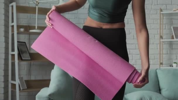 Женщина собирает ковер для йоги после окончания урока фитнеса - Кадры, видео
