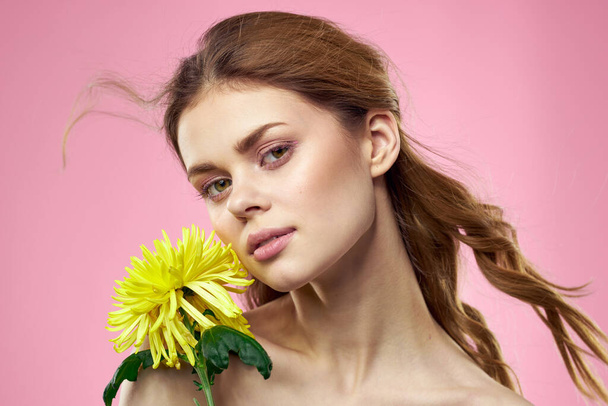 Portret kobiety z żółtymi kwiatami na różowym tle Makijaż na twarzy - Zdjęcie, obraz