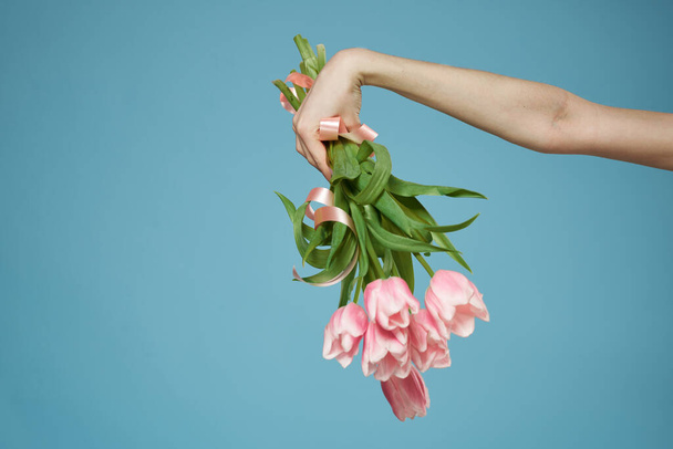 Bouquet in woman hands with gift holiday Valentine Day blue background - Photo, Image