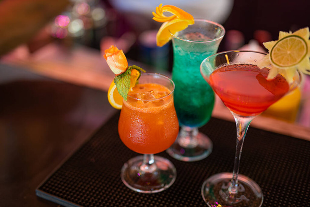 Tres coloridos cócteles gin tonic de frutas en vasos en el mostrador del bar en el pub o restaurante. Cócteles de colores brillantes - Foto, Imagen
