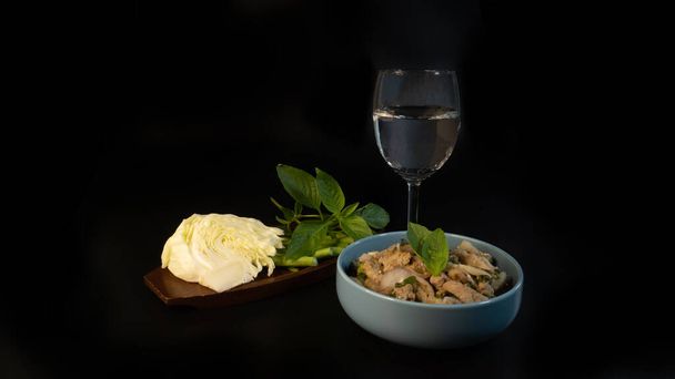 Set of thai food, slide grilled pork salad serve with sticky rice & fresh vegetables & glass of water, on the black background. - Photo, Image